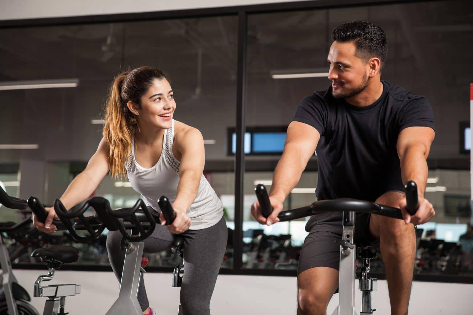 man and woman exercising on stationary bikes