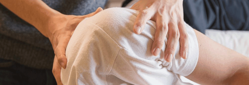 A person in a white shirt gets physical therapy with hands supporting, alongside natural pain relief supplements.