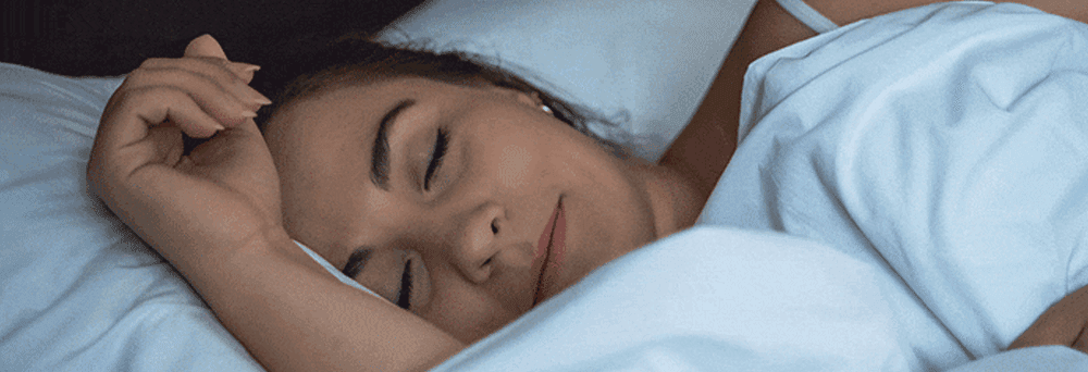 A person lies peacefully in bed under white sheets, possibly aided by natural supplements for restful sleep.