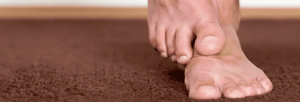 Close-up of bare feet walking on a brown carpet, highlighting comfort and foot care in a natural setting.