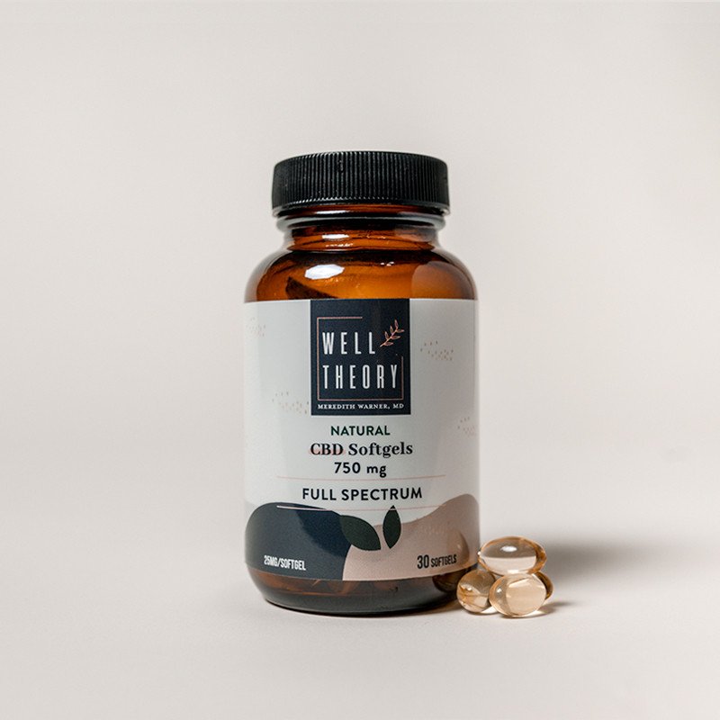 A brown "Well Theory CBD Softgels 750 mg" bottle sits beside three softgel capsules on a neutral background.