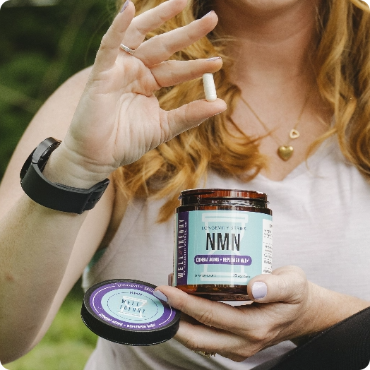 A woman holds a white capsule and an open jar labeled "NMN" supplements in her hands.