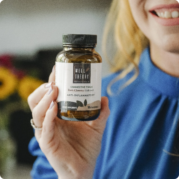 Smiling person in blue shirt holds up a bottle of Well Theory supplements for connective tissue support.