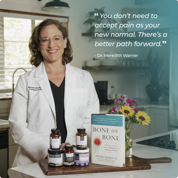 A smiling woman in a white lab coat stands in a kitchen with supplements and the book "Bone on Bone" on a tray.