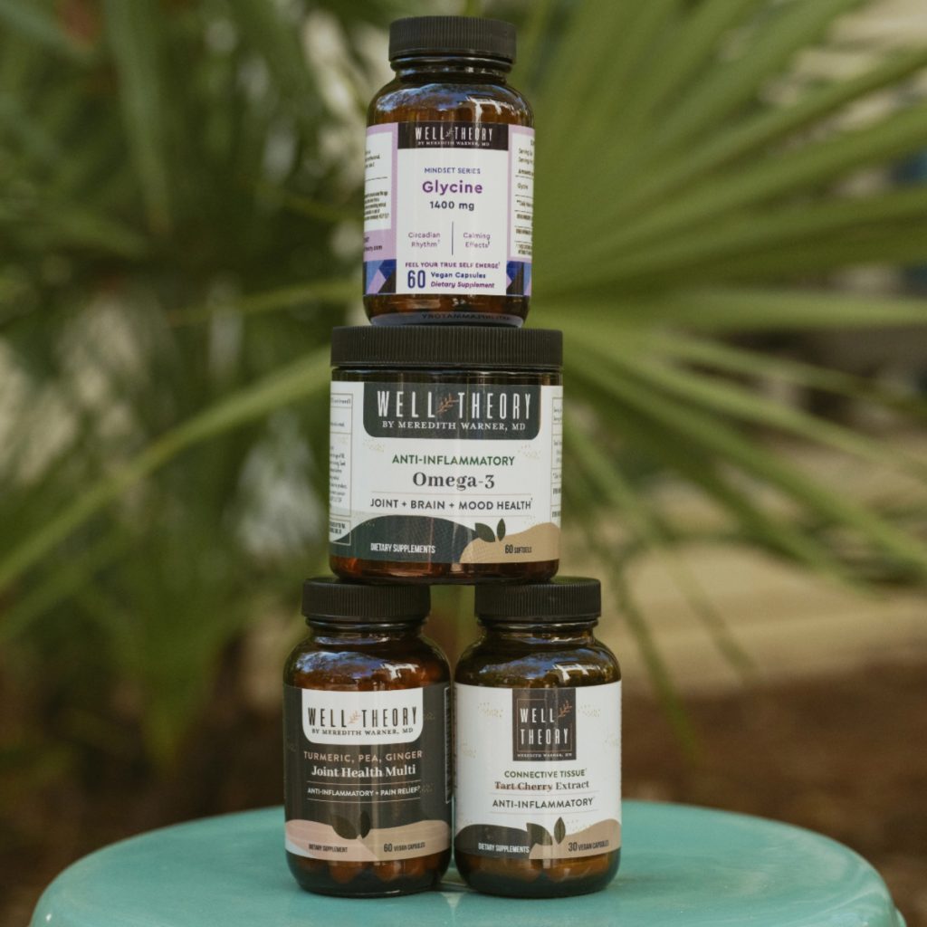 Four Well Theory supplements stacked in a pyramid on a light blue surface with a blurred green background.