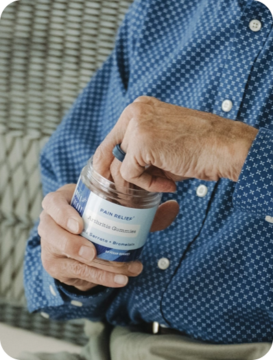 Older adult in a blue patterned shirt takes natural pain relief supplement from a bottle.