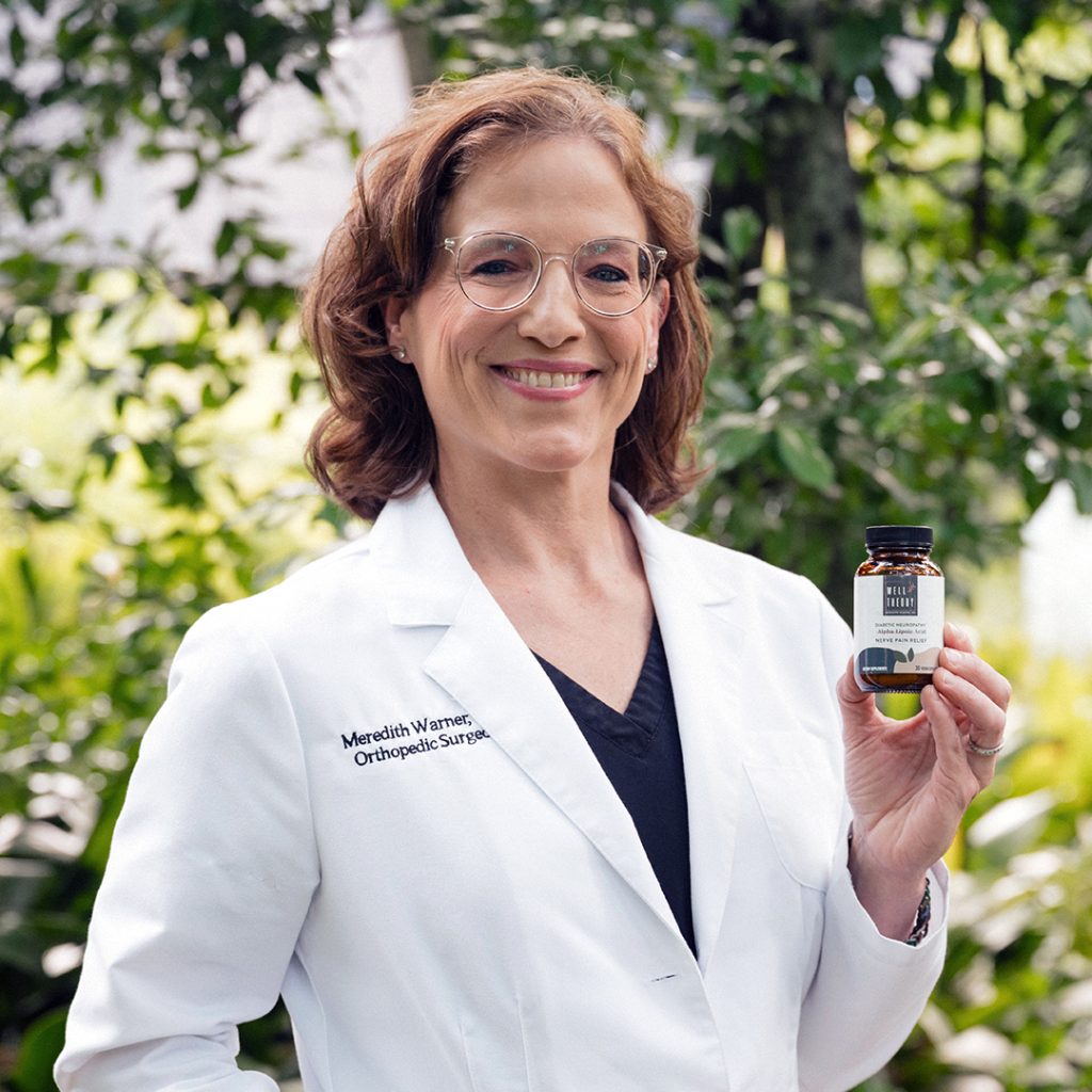 Smiling woman in a white lab coat labeled "Orthopedic Surgeon" holds a small bottle outdoors.
