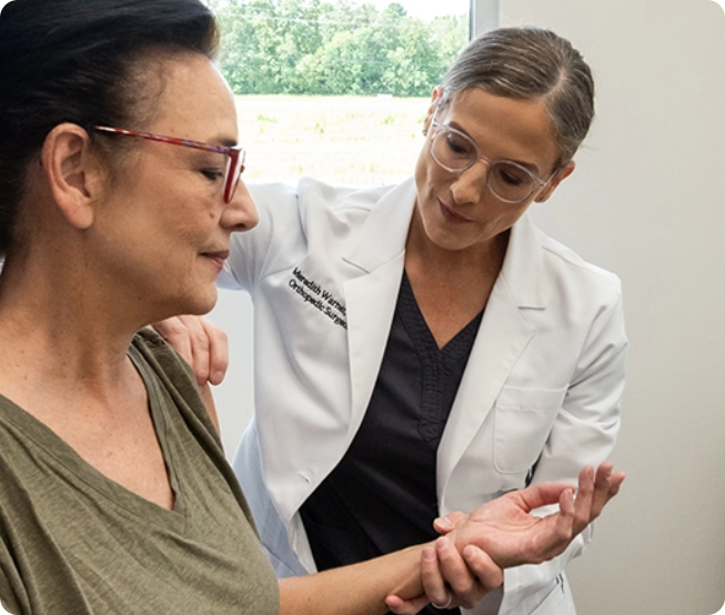 A healthcare professional checks a woman's arm and wrist in a bright office, discussing natural pain relief options.